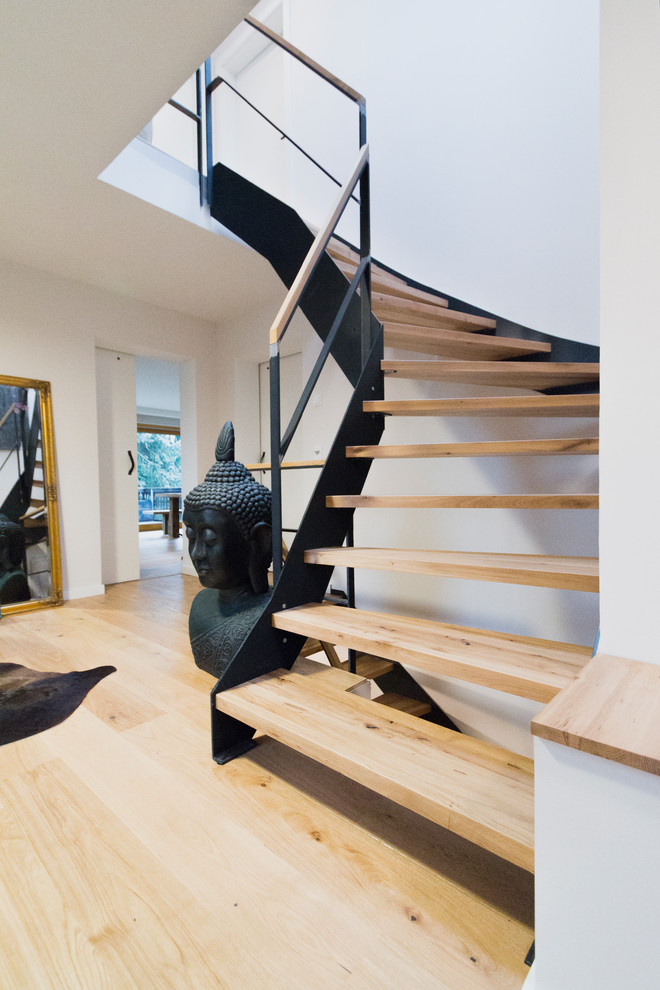 На фото: угловая лестница среднего размера в современном стиле с перилами из смешанных материалов и деревянными ступенями без подступенок с