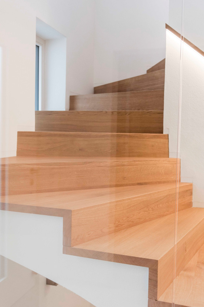 Staircase - mid-sized contemporary wooden curved glass railing and brick wall staircase idea in Munich with wooden risers