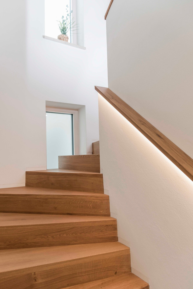 Imagen de escalera curva actual de tamaño medio con escalones de madera, contrahuellas de madera, barandilla de vidrio y ladrillo