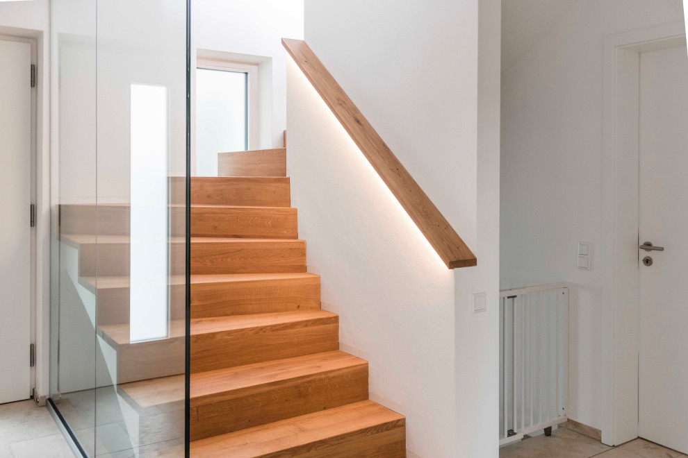 Cette photo montre un escalier courbe tendance de taille moyenne avec des marches en bois, des contremarches en bois, un garde-corps en verre et un mur en parement de brique.
