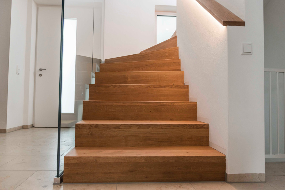 Источник вдохновения для домашнего уюта: изогнутая деревянная лестница среднего размера в современном стиле с деревянными ступенями, стеклянными перилами и кирпичными стенами