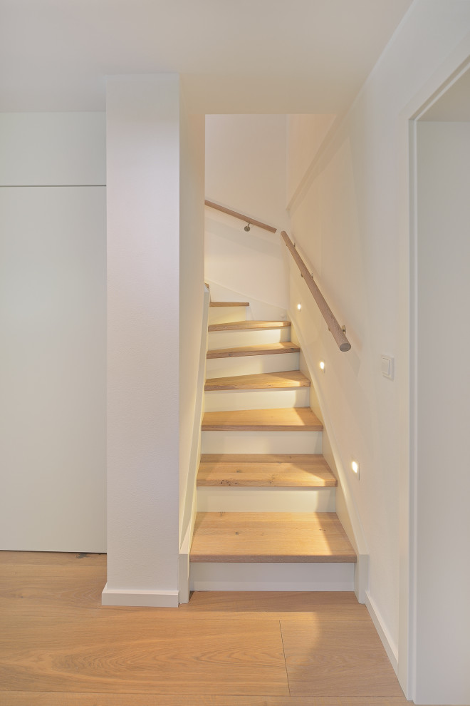 На фото: изогнутая деревянная лестница среднего размера в стиле модернизм с деревянными ступенями и деревянными перилами с