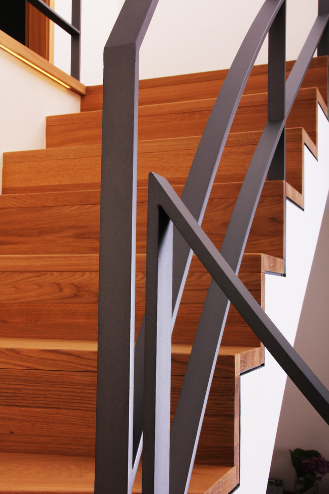 На фото: угловая лестница среднего размера в современном стиле с крашенными деревянными ступенями, крашенными деревянными подступенками и металлическими перилами