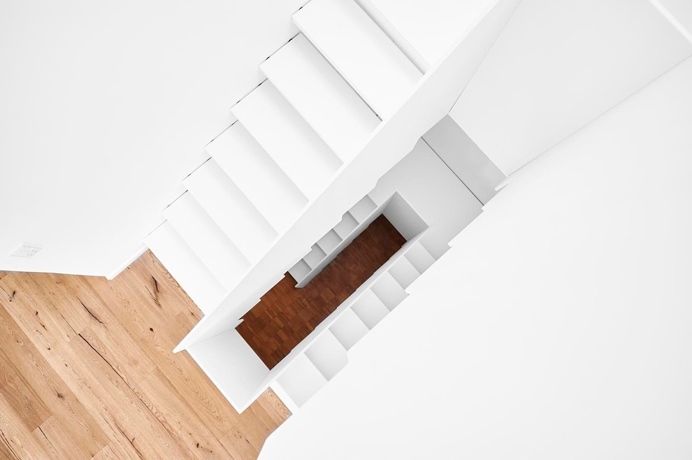 Immagine di una scala curva minimal con pedata in legno e alzata in legno