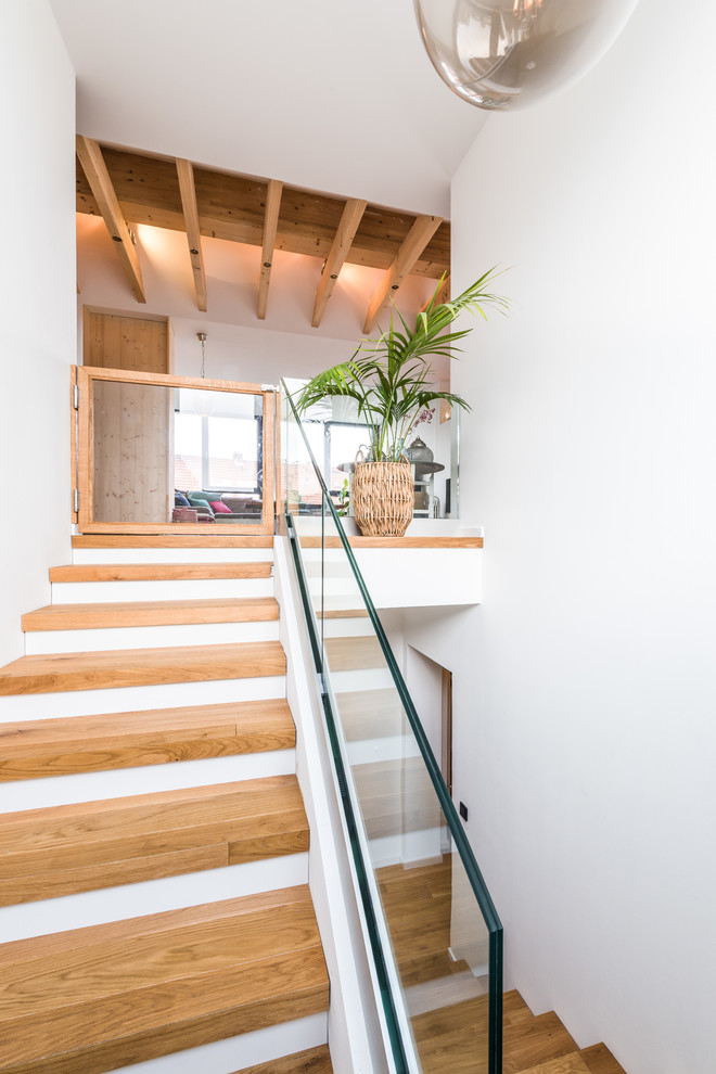 Diseño de escalera en U actual de tamaño medio con escalones de madera y barandilla de vidrio
