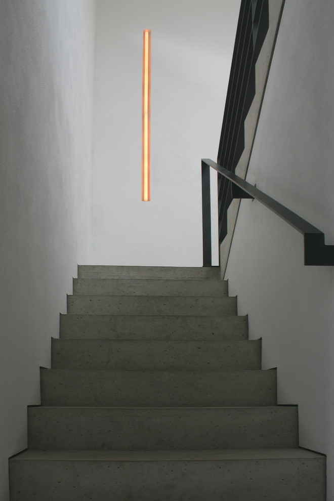 ハノーファーにある高級な巨大なコンテンポラリースタイルのおしゃれなかね折れ階段 (コンクリートの蹴込み板、金属の手すり) の写真