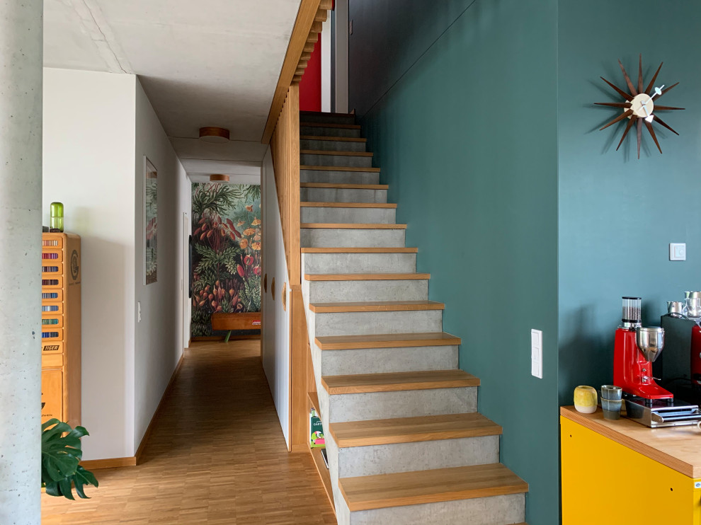 Imagen de escalera recta actual con escalones de madera, contrahuellas de hormigón, barandilla de madera y papel pintado