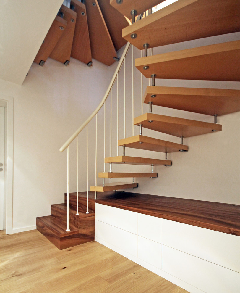 Exempel på en mellanstor modern svängd trappa i trä, med räcke i metall