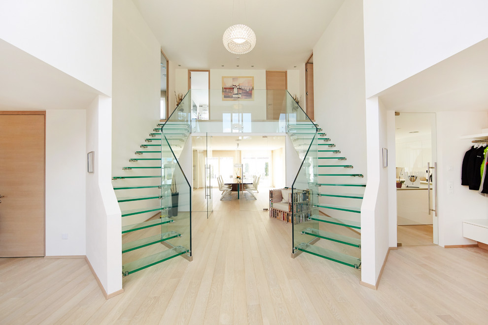 Ejemplo de escalera curva contemporánea grande con escalones de vidrio y barandilla de vidrio