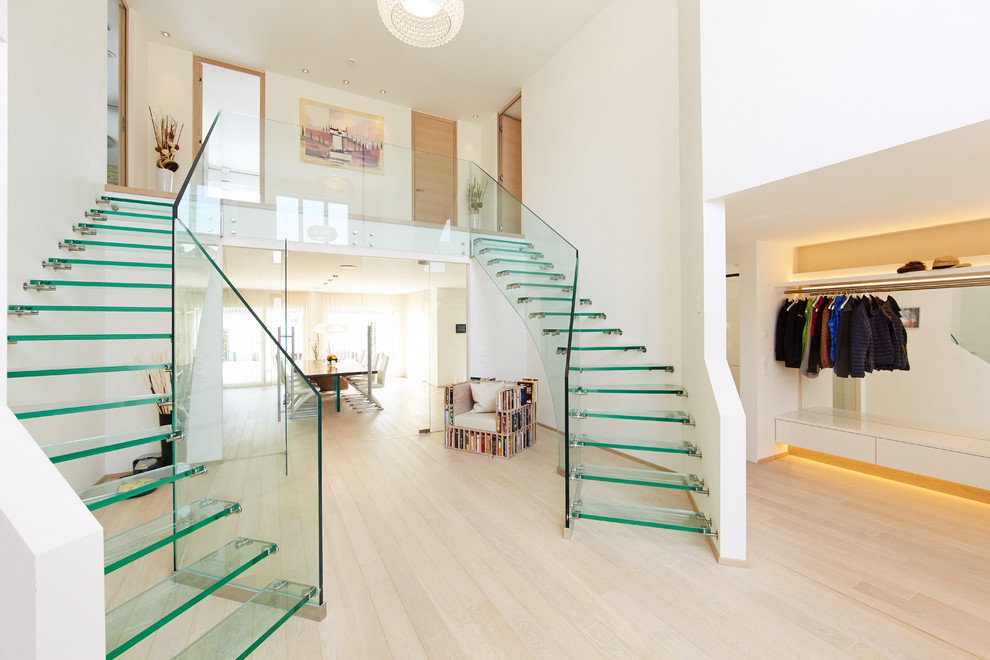 Cette photo montre un grand escalier courbe tendance avec des marches en verre et un garde-corps en verre.