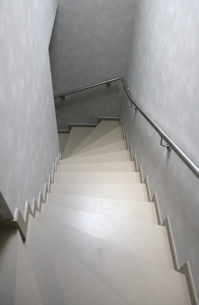 Modelo de escalera curva actual con escalones de mármol, contrahuellas de mármol y barandilla de metal