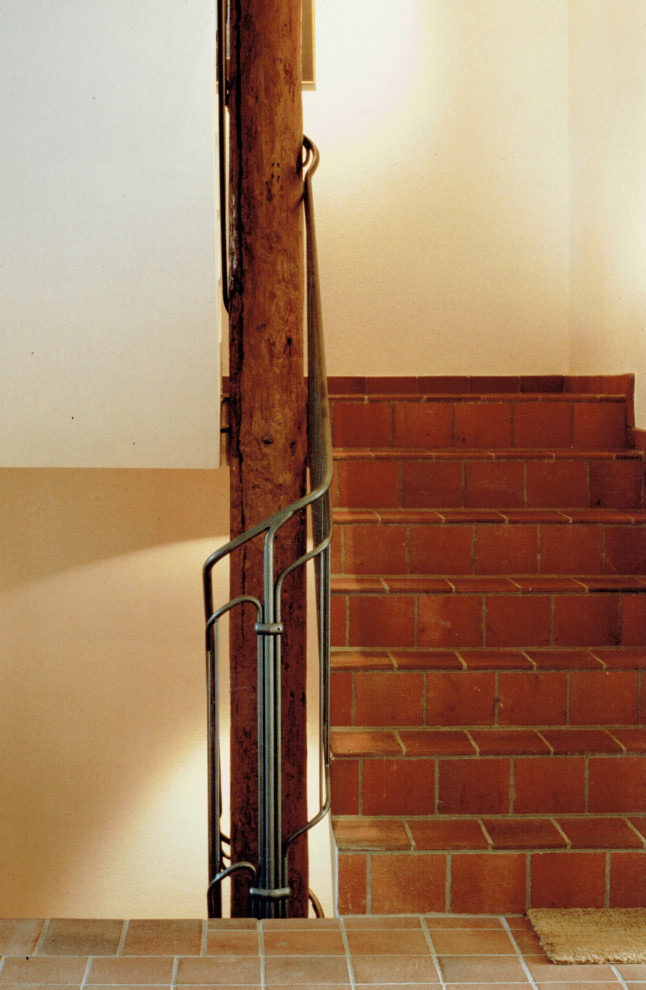 Aménagement d'un grand escalier carrelé droit campagne avec des contremarches carrelées et un garde-corps en métal.