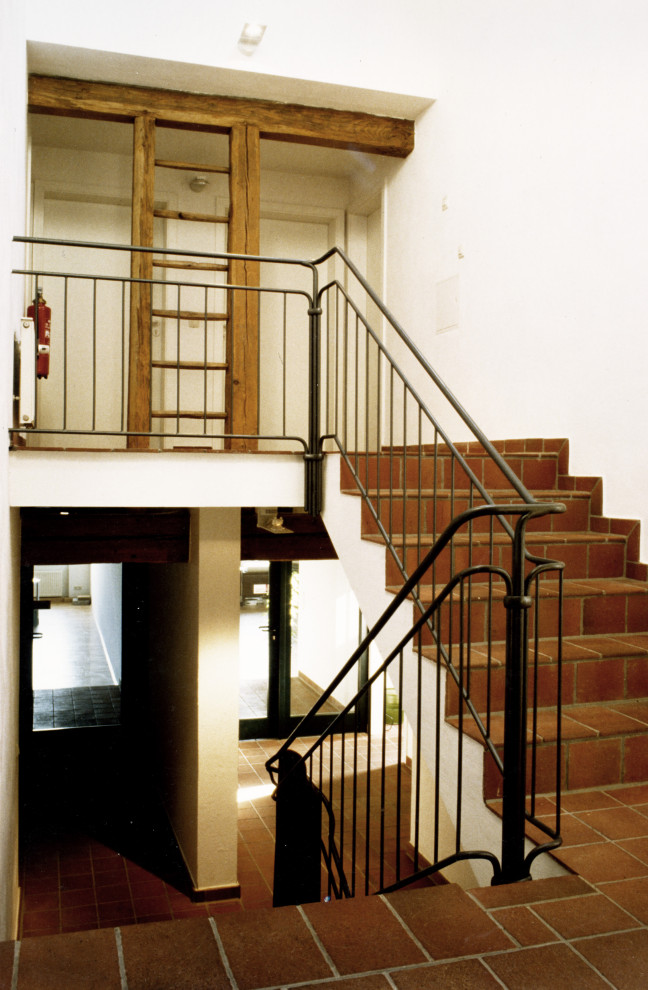 Foto på en stor lantlig rak trappa, med klinker, sättsteg i kakel och räcke i metall