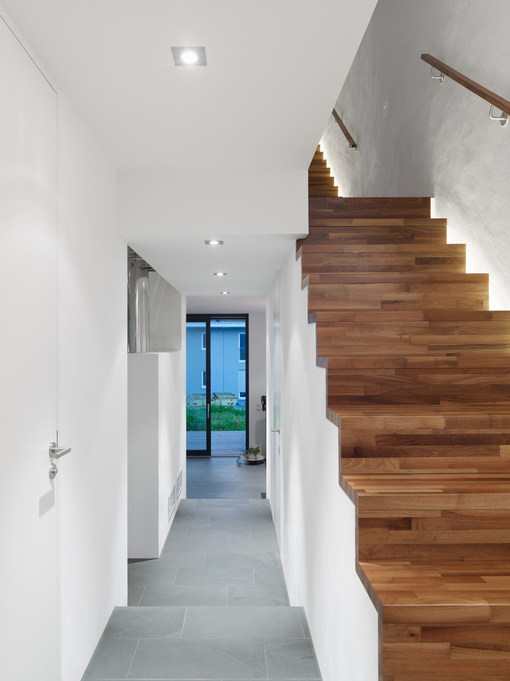 Large trendy wooden straight staircase photo in Berlin with wooden risers