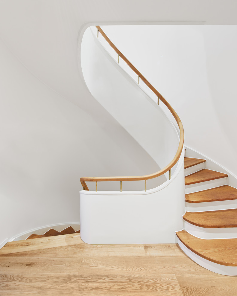 Свежая идея для дизайна: изогнутая лестница среднего размера в современном стиле с деревянными ступенями и деревянными перилами - отличное фото интерьера