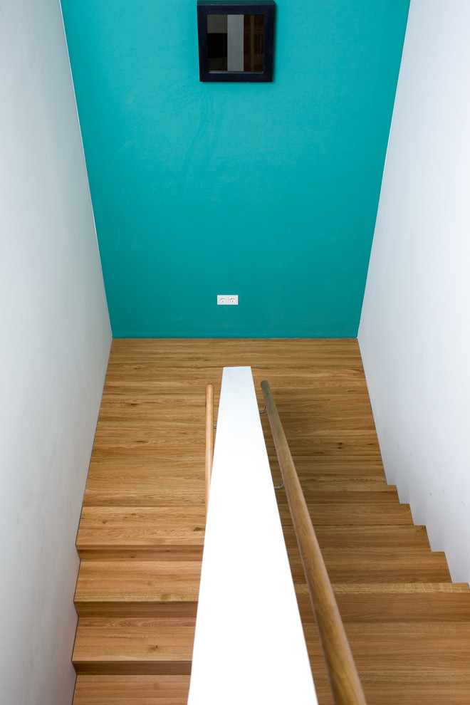 他の地域にある中くらいなコンテンポラリースタイルのおしゃれな折り返し階段 (木の蹴込み板、木材の手すり) の写真