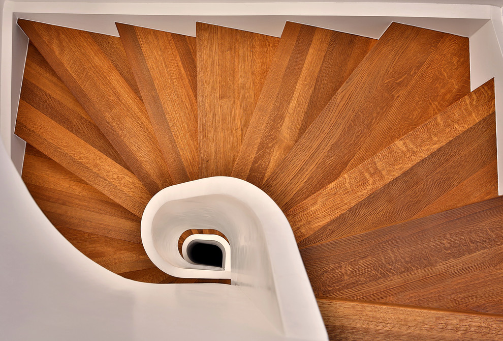 Aménagement d'un petit escalier courbe contemporain avec des marches en bois, des contremarches en bois et un garde-corps en bois.