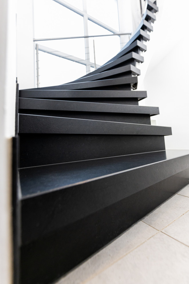 ケルンにある巨大なコンテンポラリースタイルのおしゃれなサーキュラー階段 (大理石の蹴込み板、金属の手すり) の写真