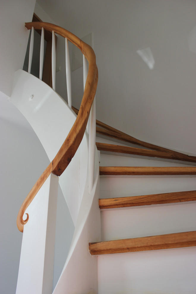 Идея дизайна: изогнутая деревянная лестница среднего размера в стиле шебби-шик с деревянными ступенями, деревянными перилами и кирпичными стенами