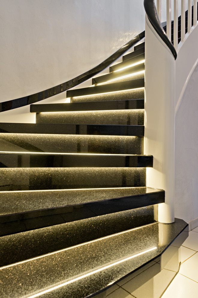 Réalisation d'un escalier courbe design en marbre de taille moyenne avec des contremarches en marbre et un garde-corps en bois.