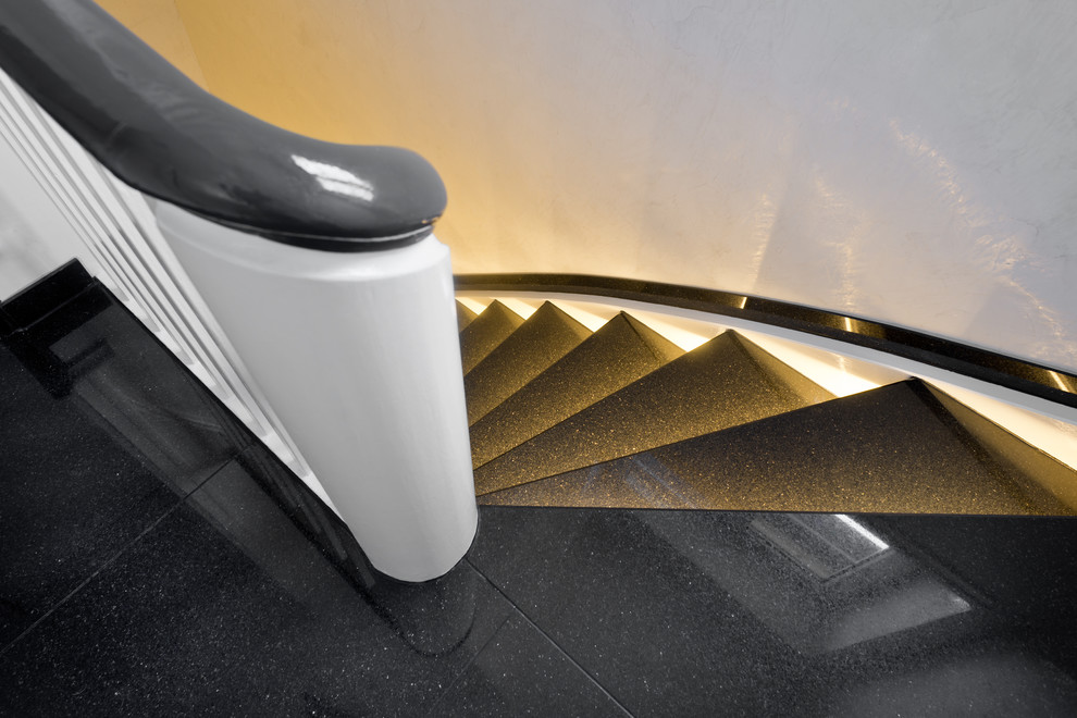 Ejemplo de escalera curva contemporánea de tamaño medio con escalones de mármol, contrahuellas de mármol y barandilla de madera