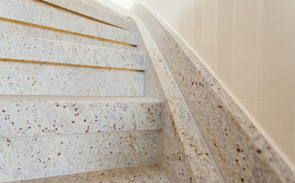 This is an example of a small country curved wood railing staircase in Dortmund with marble treads and marble risers.