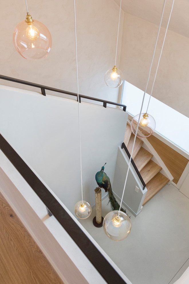 Стильный дизайн: изогнутая деревянная лестница среднего размера в скандинавском стиле с деревянными ступенями и металлическими перилами - последний тренд