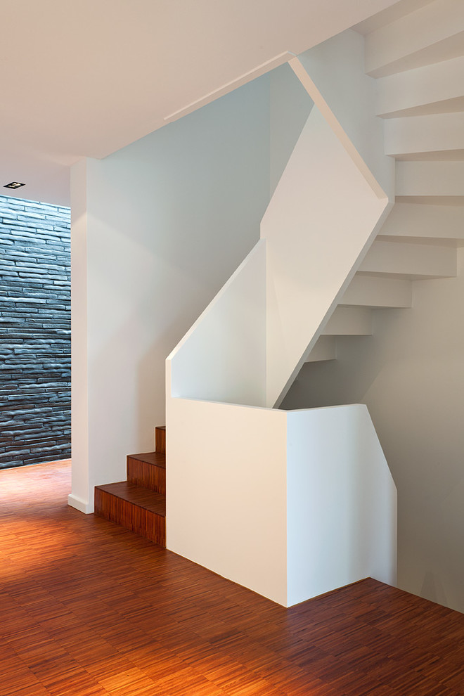 На фото: изогнутая деревянная лестница среднего размера в современном стиле с деревянными ступенями с