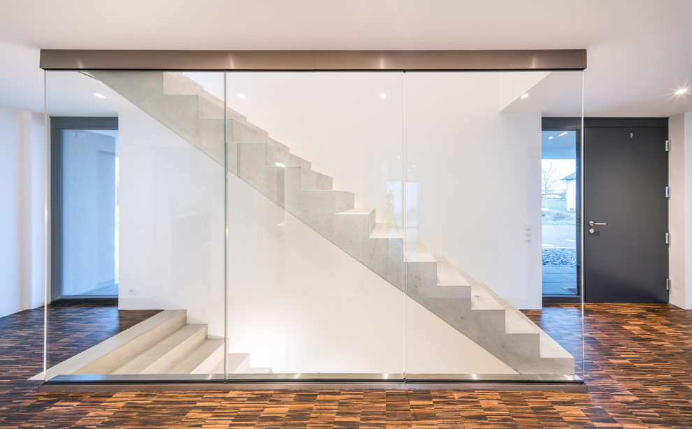 Réalisation d'un escalier droit minimaliste en béton de taille moyenne avec des contremarches en béton et un garde-corps en verre.