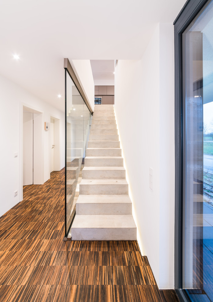 Пример оригинального дизайна: прямая бетонная лестница среднего размера в стиле модернизм с бетонными ступенями и стеклянными перилами