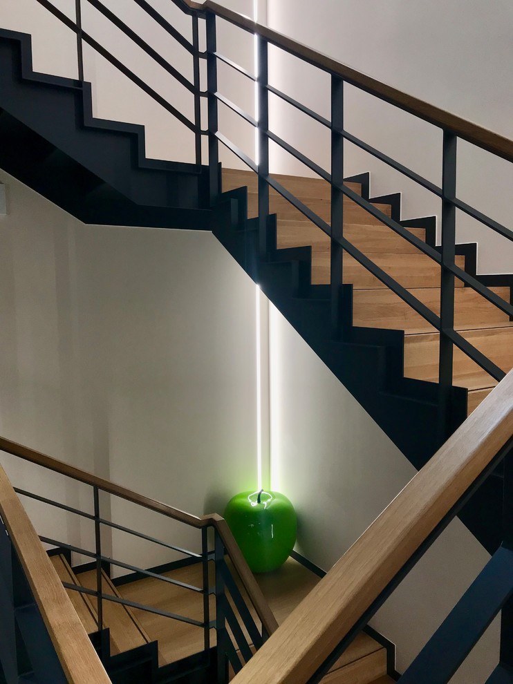 This is an example of a large modern wood curved metal railing staircase in Other with wood risers.