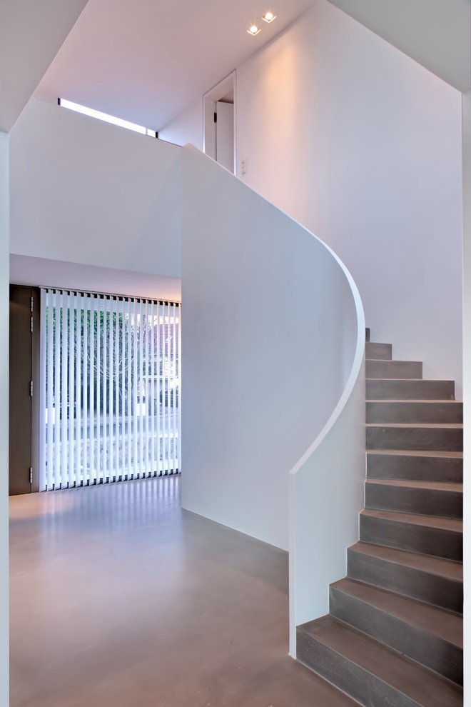 Aménagement d'un très grand escalier courbe contemporain en béton avec des contremarches en béton.