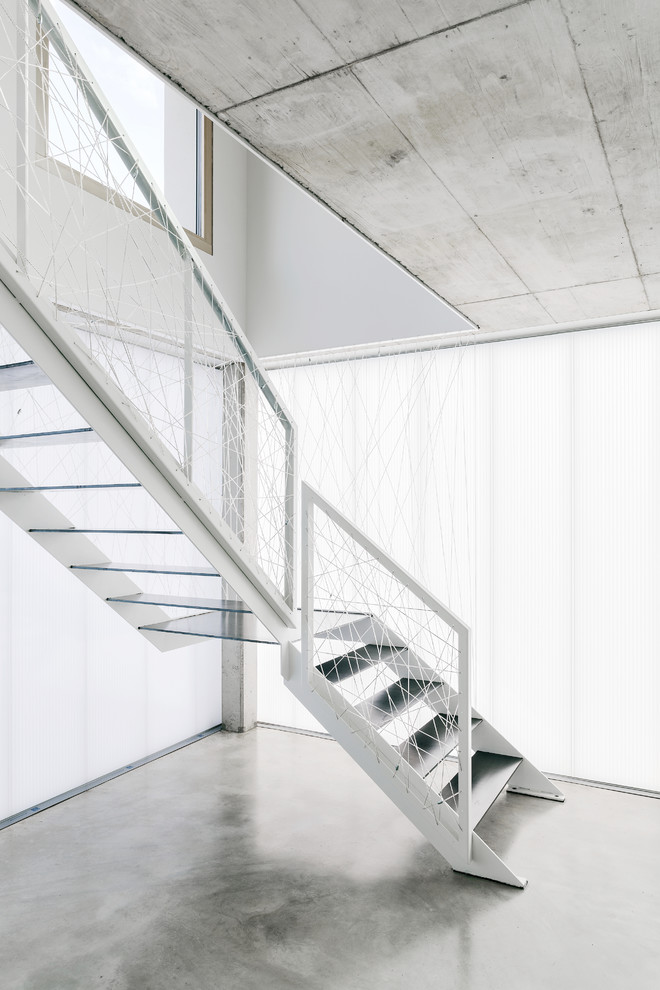 На фото: угловая лестница среднего размера в стиле модернизм с металлическими ступенями и перилами из тросов с