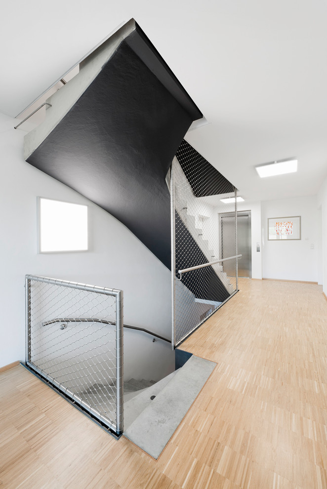 Exemple d'un escalier courbe tendance en béton de taille moyenne avec des contremarches en béton et éclairage.