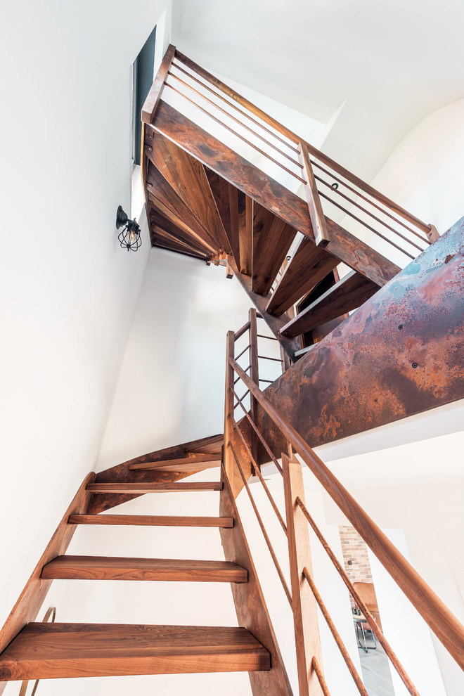 Cette image montre un escalier courbe urbain de taille moyenne avec des marches en bois et un garde-corps en métal.