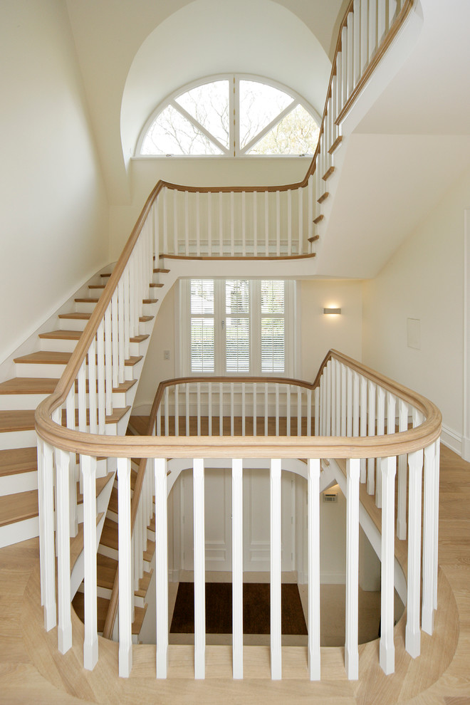 Idée de décoration pour un très grand escalier courbe tradition avec des marches en bois et des contremarches en bois.