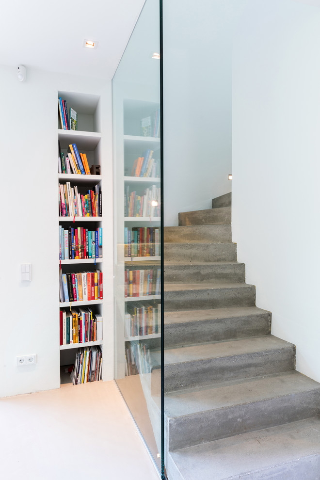 Exemple d'un escalier courbe industriel en béton de taille moyenne avec des contremarches en béton et un garde-corps en verre.