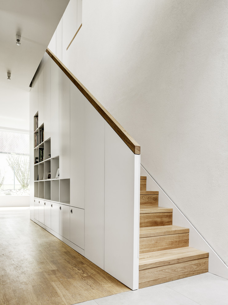 Réalisation d'un escalier droit design de taille moyenne avec des marches en bois, des contremarches en bois et rangements.