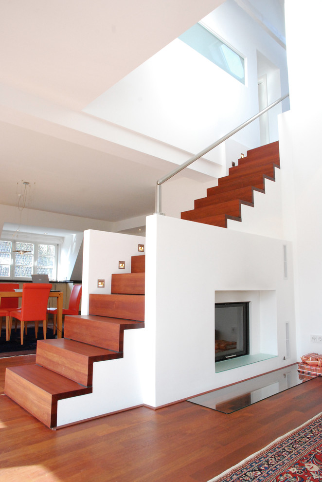 Aménagement d'un grand escalier droit contemporain avec des marches en bois, des contremarches en bois et un téléviseur en dessous.
