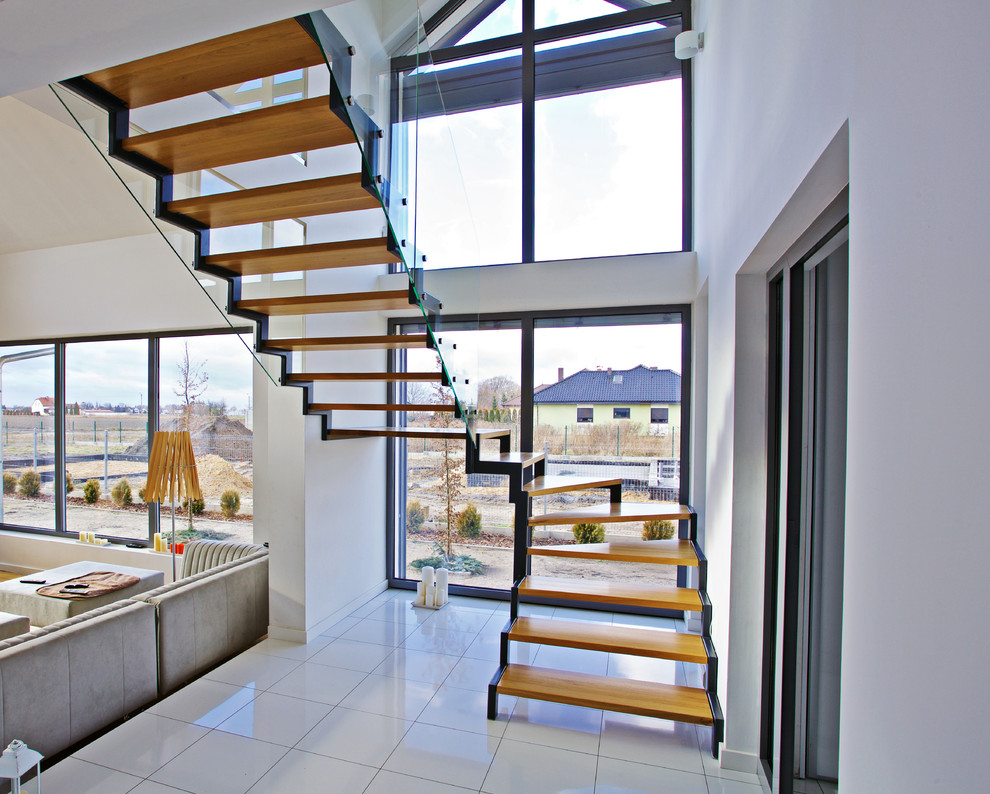 Стильный дизайн: большая изогнутая лестница в современном стиле с деревянными ступенями без подступенок - последний тренд