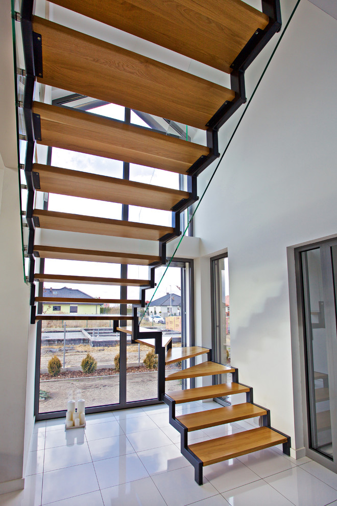 Cette image montre un grand escalier sans contremarche design en U avec des marches en bois.