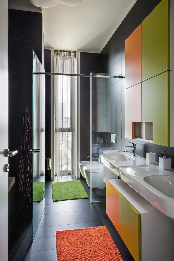 Inspiration för mellanstora moderna toaletter, med släta luckor, gröna skåp, en bidé, svart kakel, keramikplattor, svarta väggar, klinkergolv i keramik, ett väggmonterat handfat och svart golv