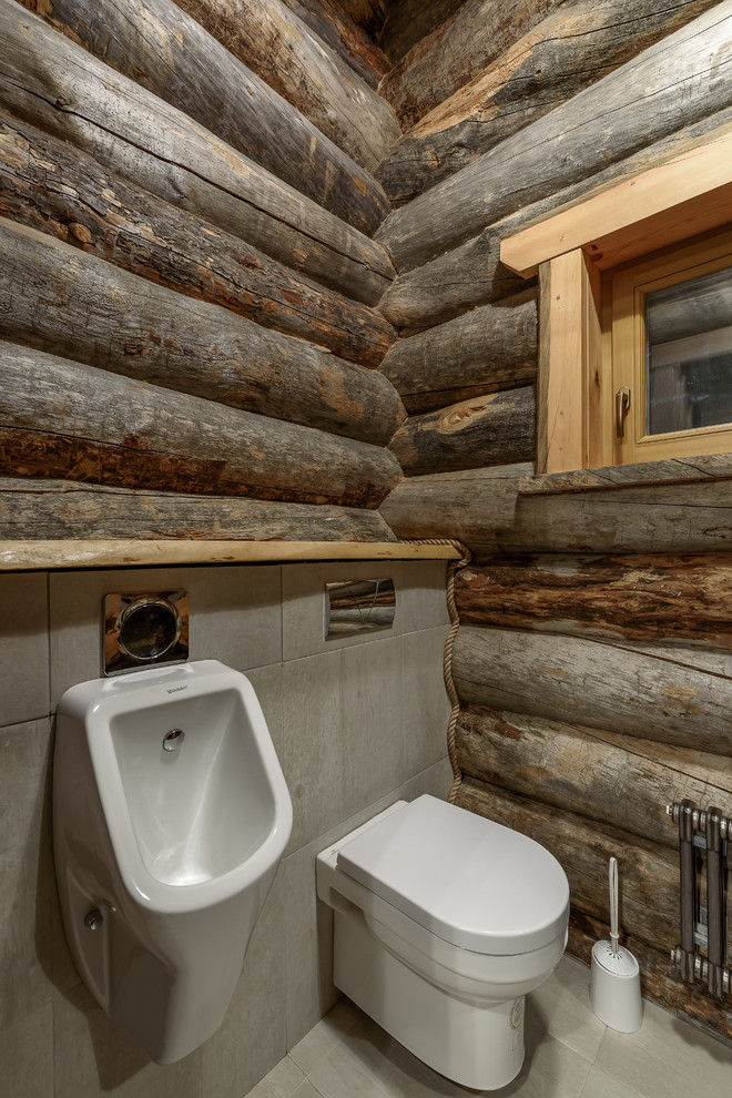 Inredning av ett rustikt toalett, med ett fristående handfat, ett urinoar, grå väggar och grått golv