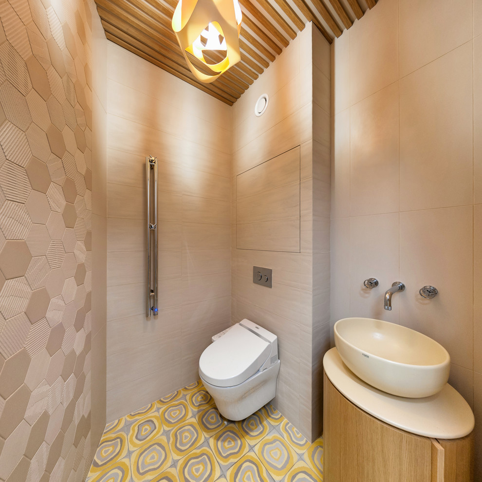 На фото: туалет среднего размера в современном стиле с инсталляцией, бежевой плиткой, бежевыми стенами, полом из керамической плитки и разноцветным полом