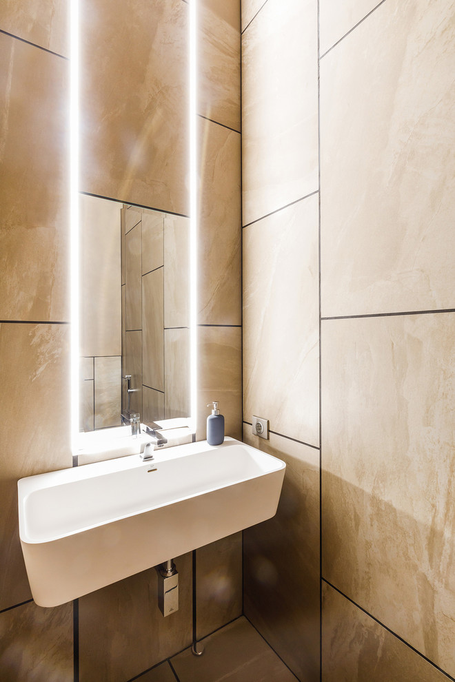 Ispirazione per un bagno di servizio design con piastrelle beige, piastrelle marroni, lavabo sospeso e pavimento marrone