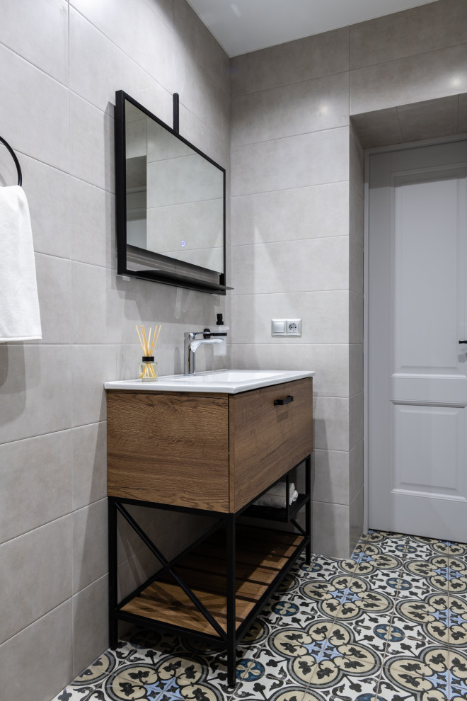 Example of a mid-sized trendy gray tile and ceramic tile porcelain tile and gray floor powder room design in Moscow with flat-panel cabinets, medium tone wood cabinets, a two-piece toilet, gray walls, a drop-in sink, solid surface countertops and white countertops