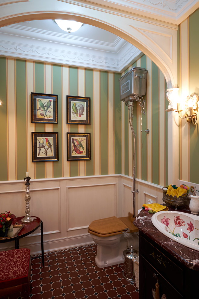 Imagen de aseo tradicional con sanitario de dos piezas, paredes verdes, lavabo encastrado y suelo multicolor