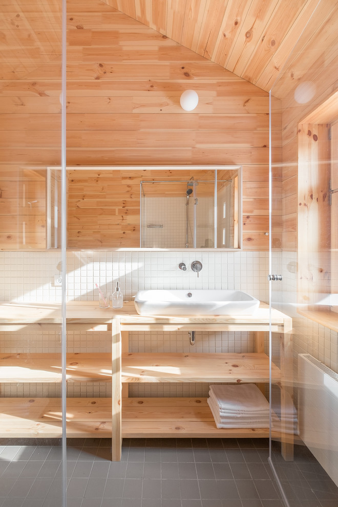 Пример оригинального дизайна: большой туалет в стиле кантри с белой плиткой, керамогранитной плиткой, накладной раковиной и столешницей из дерева