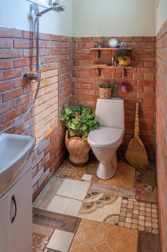 На фото: туалет среднего размера в стиле кантри с унитазом-моноблоком, оранжевой плиткой, серыми стенами, полом из керамической плитки, накладной раковиной и разноцветным полом с