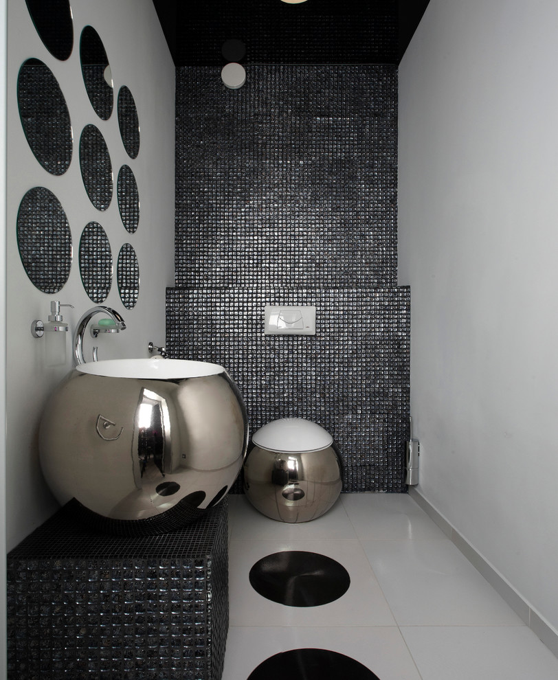 他の地域にあるコンテンポラリースタイルのおしゃれなトイレ・洗面所 (ベッセル式洗面器、黒いタイル、モザイクタイル、グレーの壁) の写真